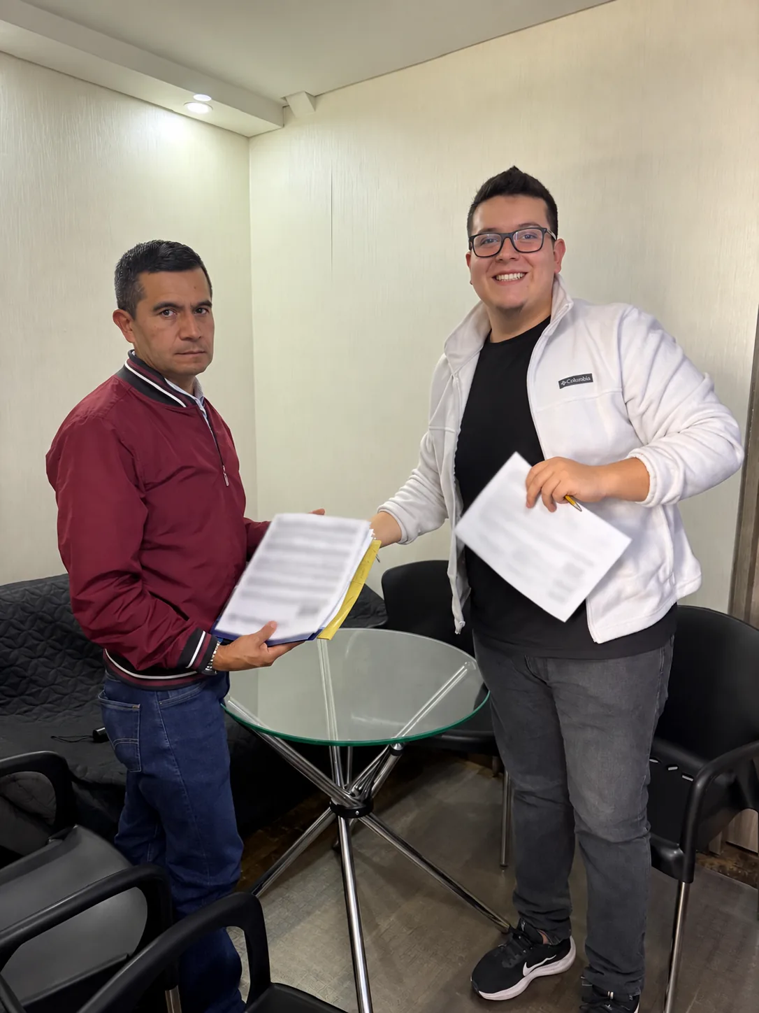 Integrante del equipo junto a un cliente con documentos en la oficina